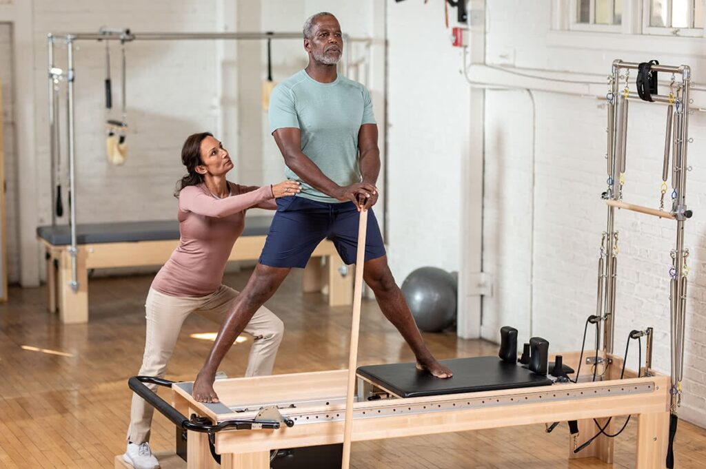 Juhendaja abistab klienti Clinical Reformer seadmel koos torniga.