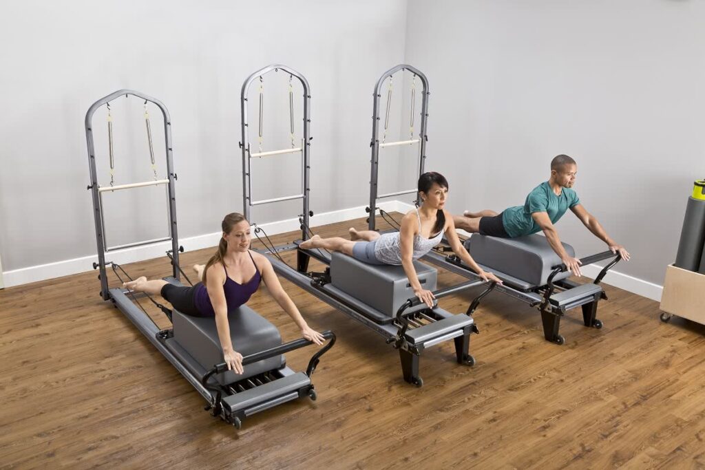 Three people exercising on Allegro Tower of Power reformers.