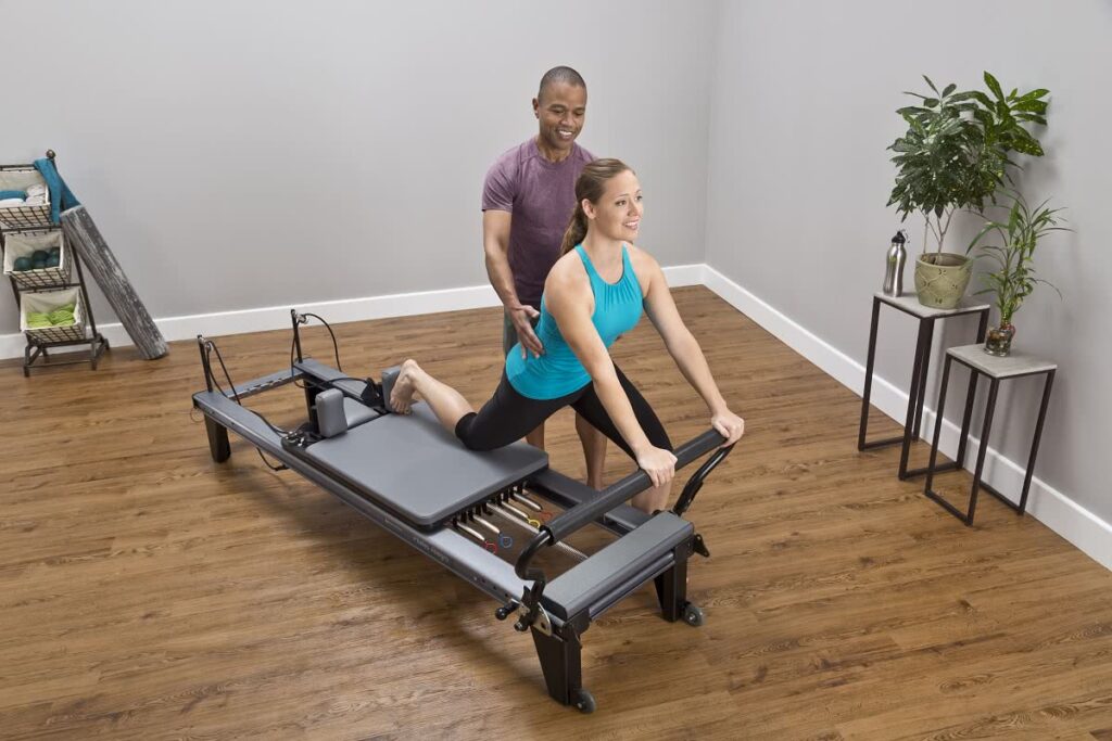 Instructor assists woman on Allegro Tower of Power reformer.
