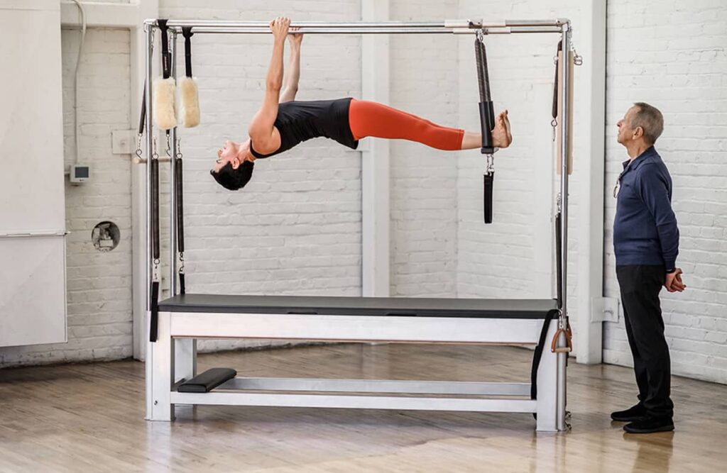 Инструктор демонстрирует упражнение на тренажёре Contrology Cadillac в студии.