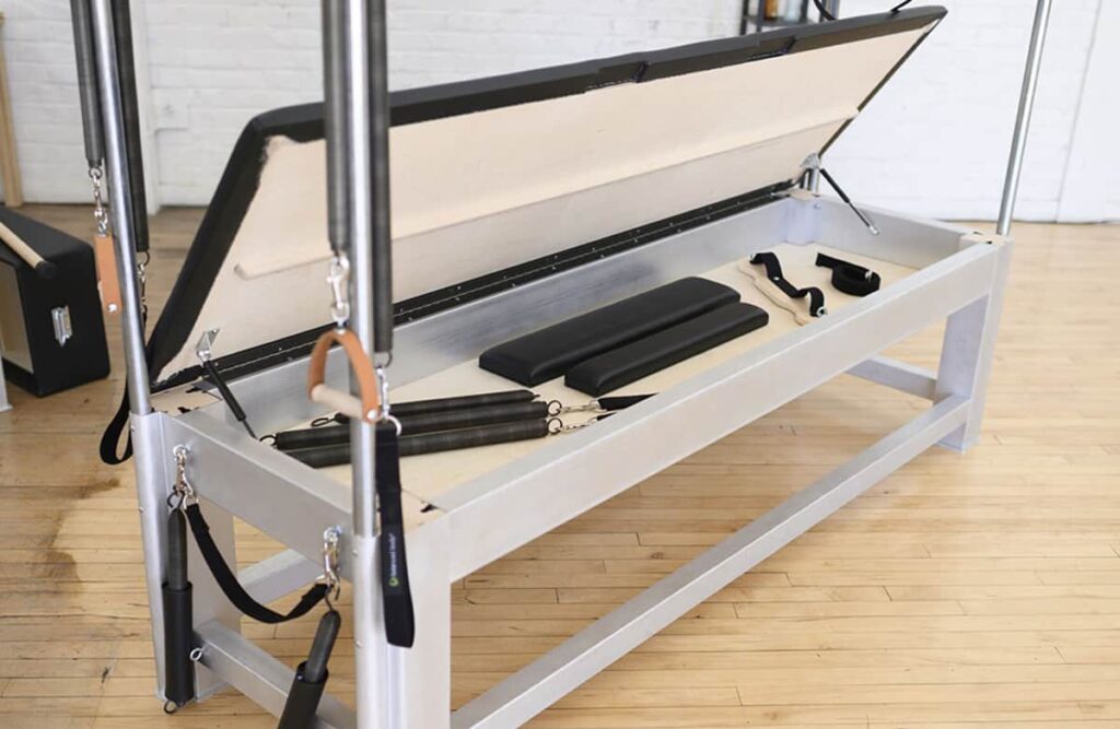 Открытая коробка Contrology Cadillac с аксессуарами для пилатеса внутри.