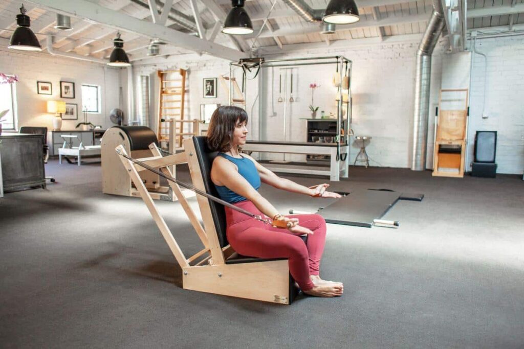 Инструктор по пилатесу использует контурные кожаные ручки Contrology на тренировочном стуле.