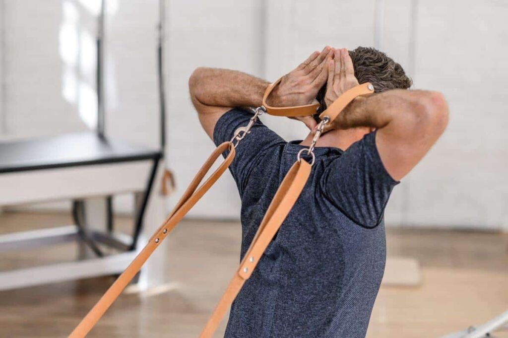 Mees kasutab Contrology nahast käepidemeid Pilatese harjutuseks