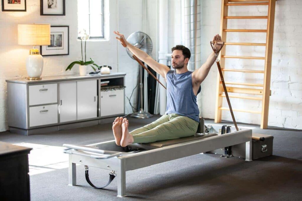 Mees kasutab Contrology nahast käepidemeid Pilates reformeril.