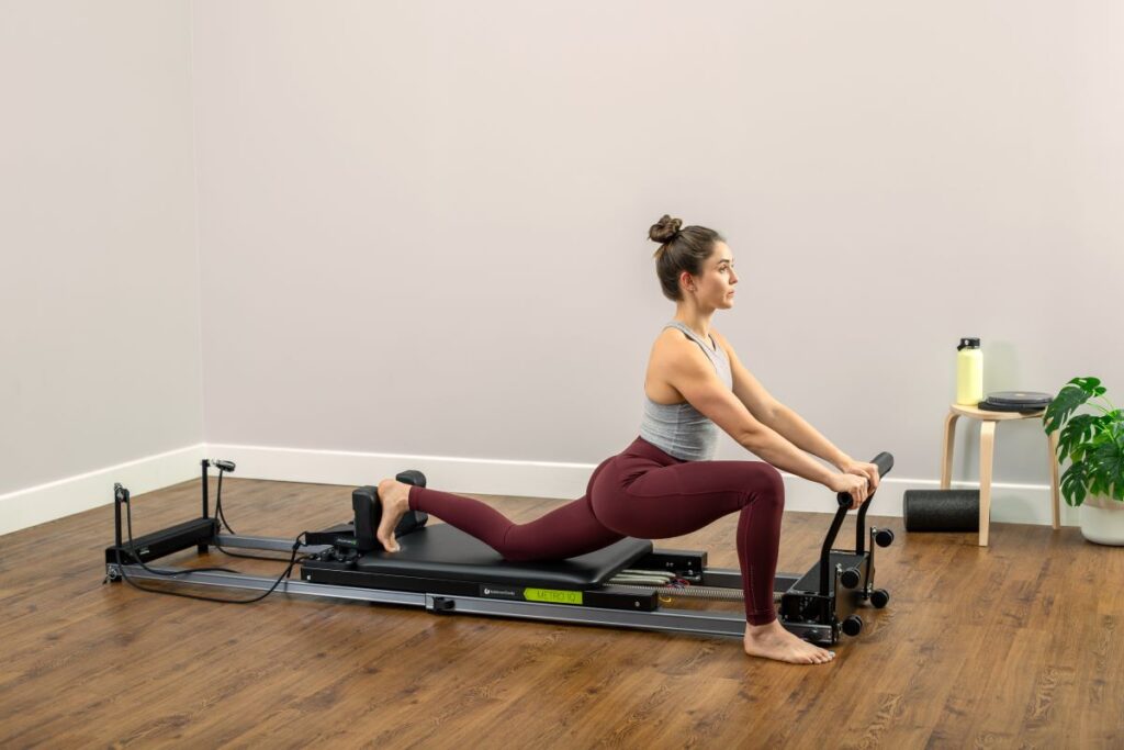 Женщина занимается на тренажёре Metro IQ Reformer в домашней обстановке.