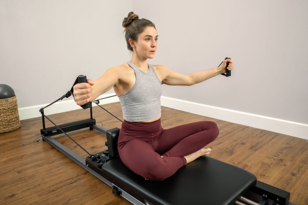 Женщина занимается на тренажёре Pilates Metro IQ Reformer в домашней обстановке.