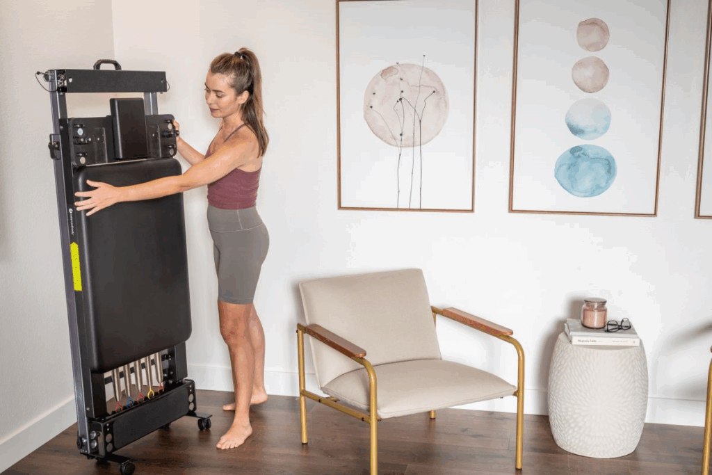 Женщина складывает тренажёр Metro IQ Reformer для удобного хранения дома.