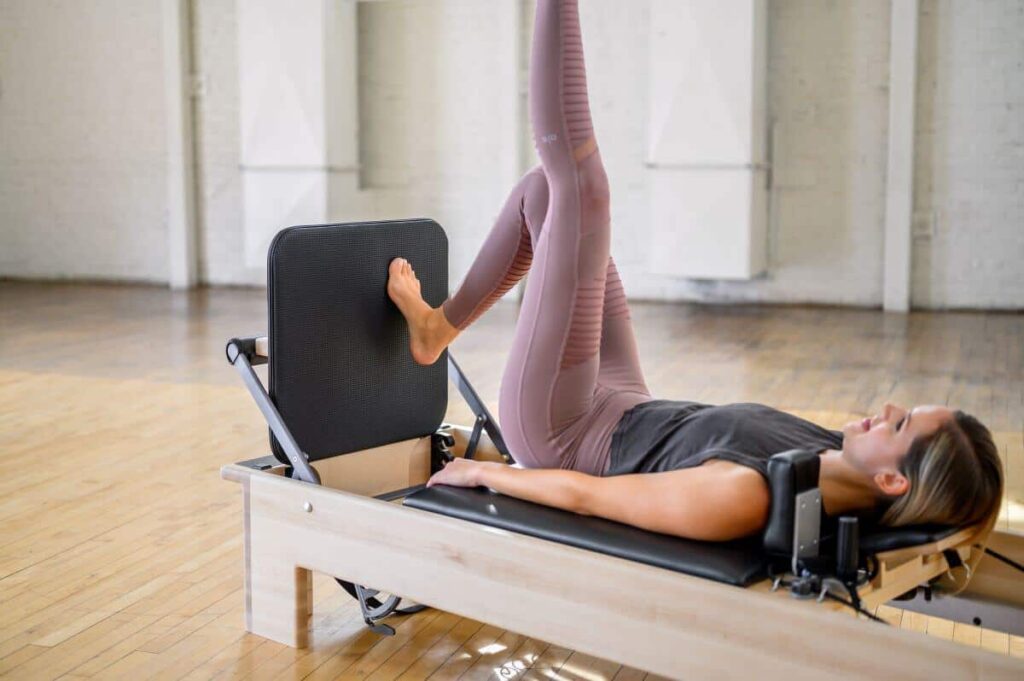 Person using Studio Reformer Jumpboard for Pilates exercise.