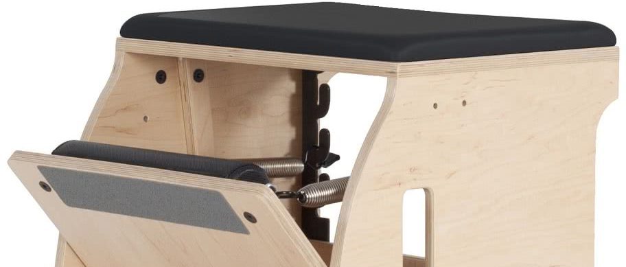 Pilateseseade puidust raamiga ja musta polsterdatud istmega.