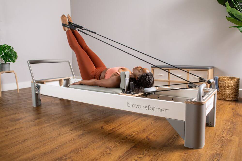 User exercising on a Bravo Reformer in a Pilates studio.