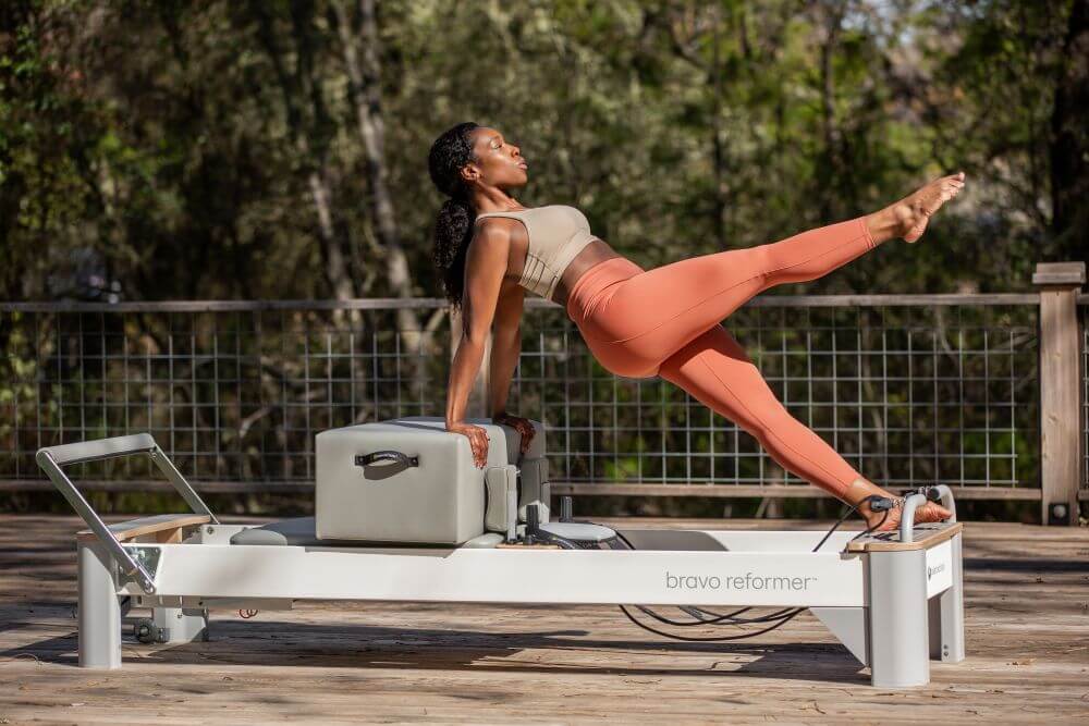 User practicing Pilates on Bravo Reformer outside on a deck.