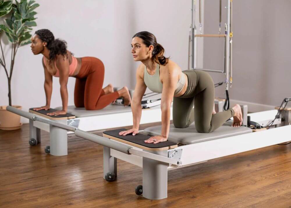 Две женщины занимаются на удлинителях платформы Bravo Reformer.