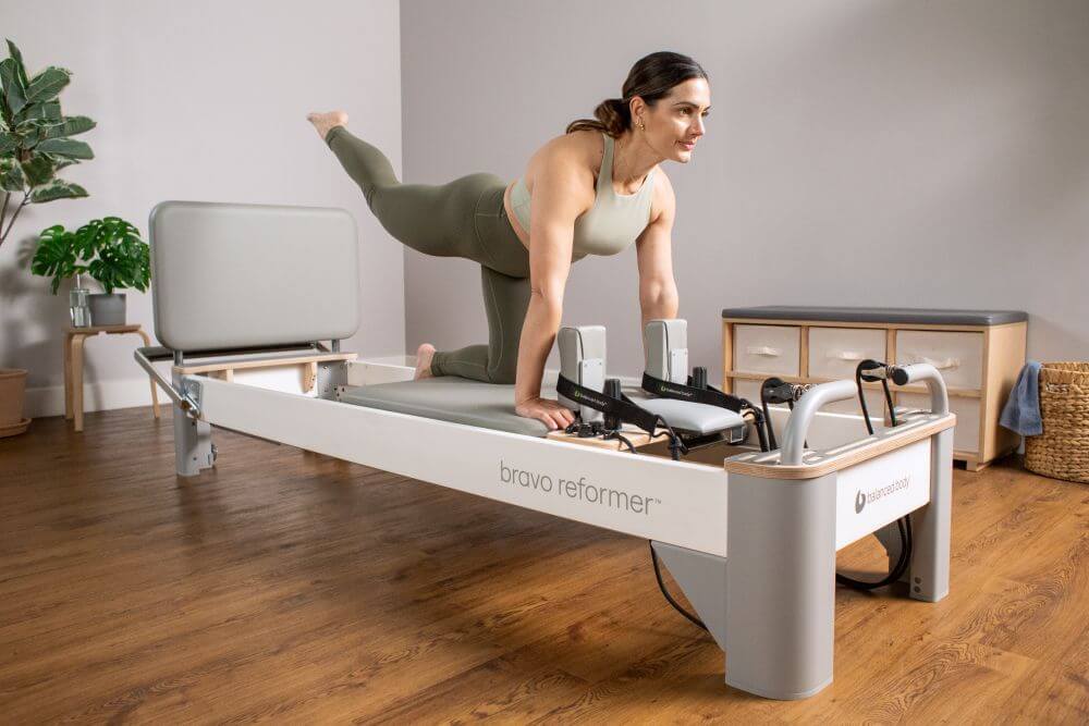 Женщина выполняет упражнения Пилатеса на Bravo Reformer с Jumpboard
